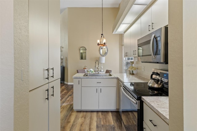 kitchen featuring white cabinetry, sink, stainless steel appliances, and decorative light fixtures