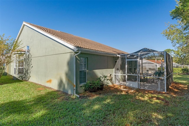 view of side of home featuring a lawn and glass enclosure