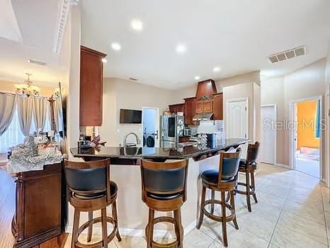 kitchen featuring a notable chandelier, kitchen peninsula, stainless steel fridge, a breakfast bar, and light tile patterned floors