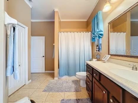 bathroom with toilet, vanity, tile patterned floors, and ornamental molding