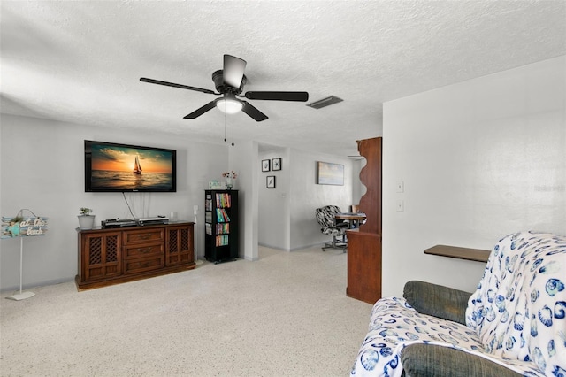 living area with a textured ceiling and ceiling fan