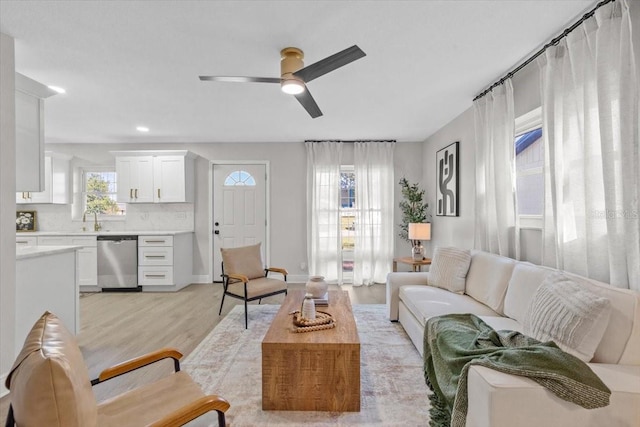 living room with ceiling fan, light wood-type flooring, and sink