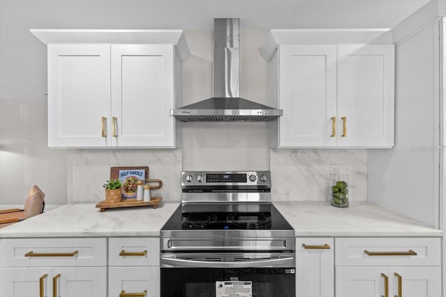 kitchen with stainless steel range with electric stovetop, white cabinetry, and wall chimney range hood