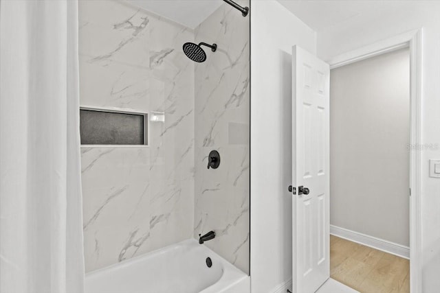 bathroom featuring wood-type flooring and tiled shower / bath