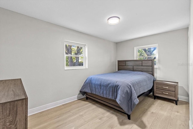 bedroom with light hardwood / wood-style floors and multiple windows