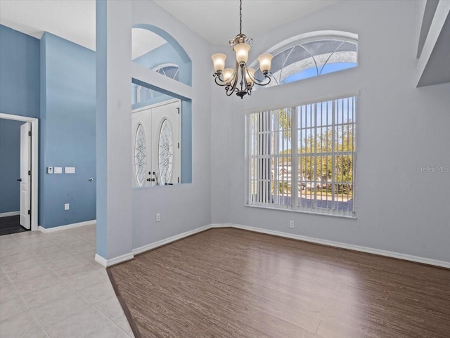 unfurnished room with plenty of natural light, light hardwood / wood-style floors, and a notable chandelier