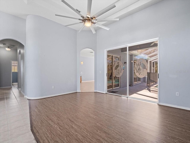 empty room featuring beamed ceiling, wood-type flooring, and ceiling fan