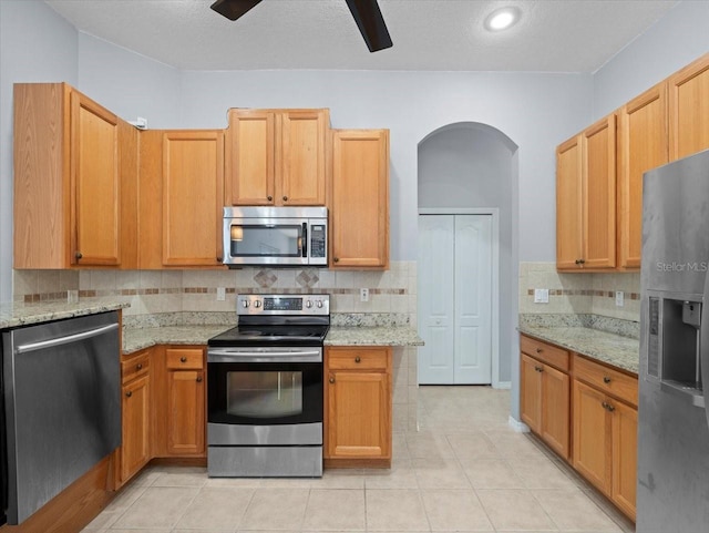 kitchen with light stone countertops, a textured ceiling, stainless steel appliances, and light tile patterned flooring