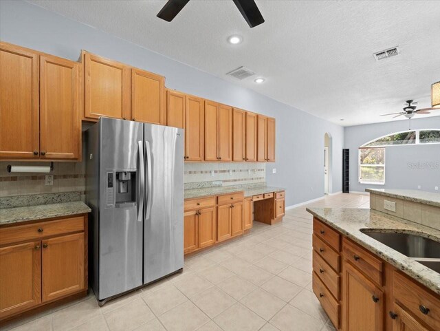 kitchen featuring light stone countertops, stainless steel fridge with ice dispenser, tasteful backsplash, and ceiling fan