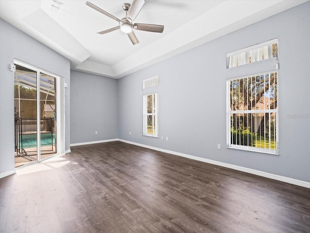 spare room featuring ceiling fan, a raised ceiling, and dark wood-type flooring