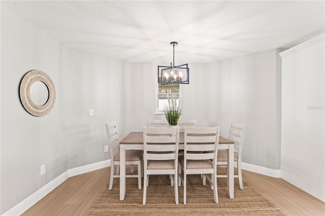 dining area featuring wood-type flooring, a textured ceiling, and an inviting chandelier