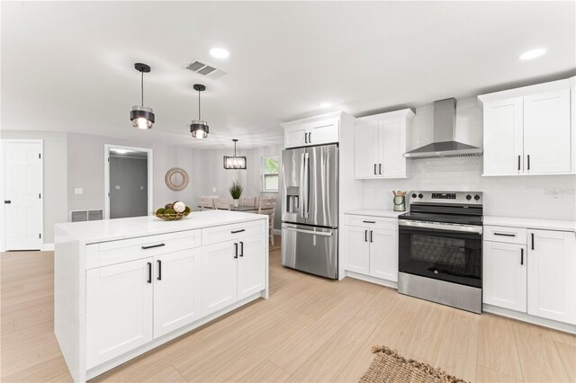 kitchen featuring white cabinetry, pendant lighting, stainless steel appliances, and wall chimney range hood