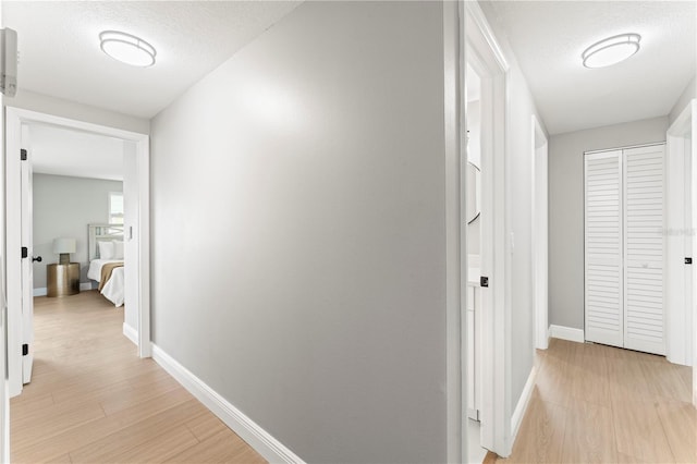 hall with a textured ceiling and light hardwood / wood-style floors