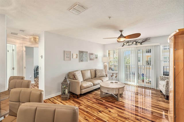 living room featuring ceiling fan, wood-type flooring, and a textured ceiling