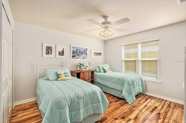 bedroom featuring a textured ceiling, light hardwood / wood-style flooring, a closet, and ceiling fan