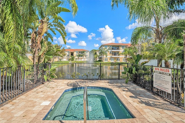 view of swimming pool with a water view and a hot tub