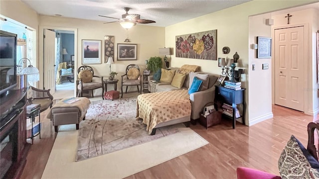 interior space featuring ceiling fan, a textured ceiling, baseboards, and wood finished floors