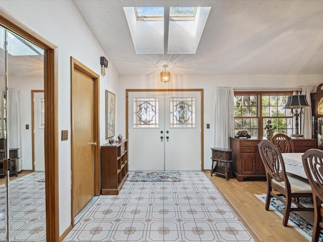 entryway featuring a textured ceiling, french doors, light hardwood / wood-style flooring, and a skylight