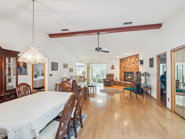 dining space with a fireplace, light wood-type flooring, lofted ceiling with beams, and ceiling fan