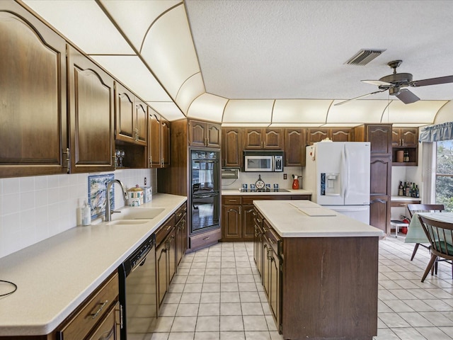 kitchen featuring stainless steel appliances, ceiling fan, sink, a center island, and light tile patterned flooring