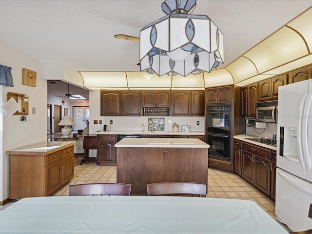 kitchen featuring backsplash, black appliances, sink, ceiling fan, and a kitchen island