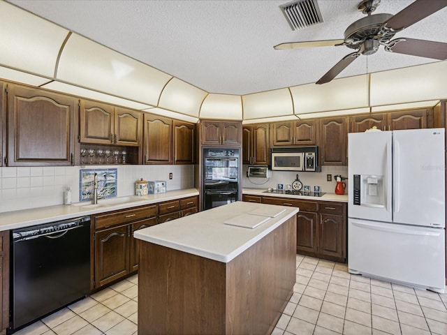 kitchen featuring a center island, black appliances, sink, light tile patterned flooring, and dark brown cabinetry