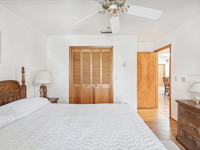 bedroom featuring ceiling fan, a closet, a textured ceiling, and light hardwood / wood-style flooring