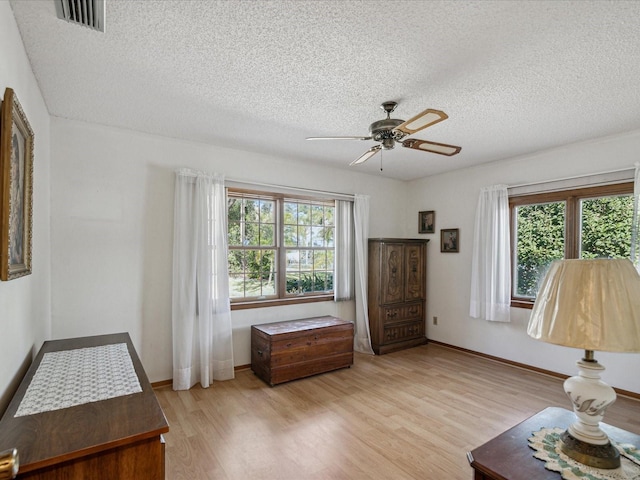 sitting room with ceiling fan, a textured ceiling, and light wood-type flooring