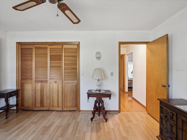 bedroom featuring a textured ceiling, light hardwood / wood-style floors, a closet, and ceiling fan