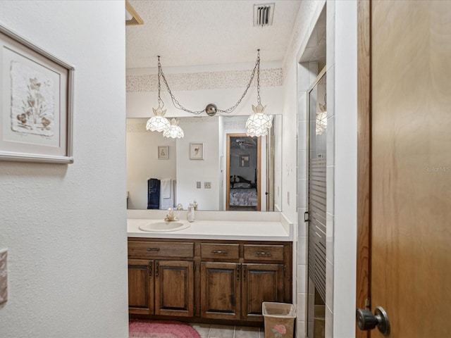 bathroom with a shower with door, vanity, a chandelier, and a textured ceiling