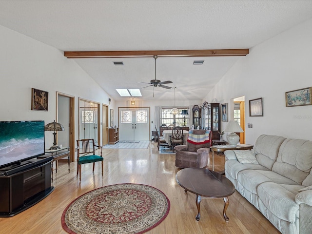 living room with lofted ceiling with skylight, light hardwood / wood-style flooring, and ceiling fan