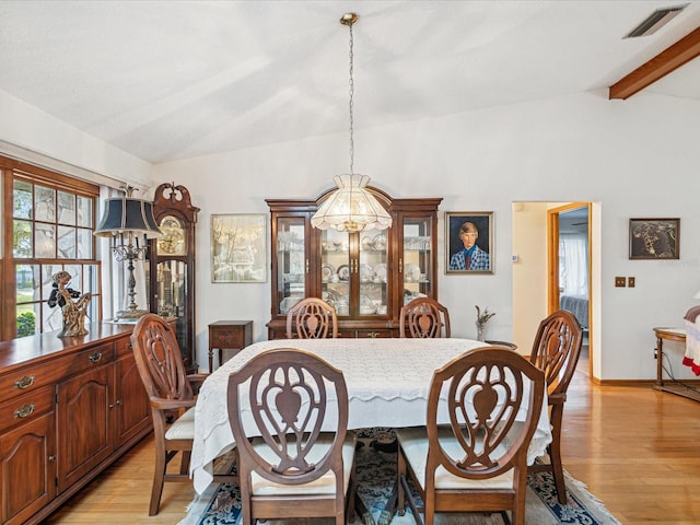 dining area featuring lofted ceiling with beams, light hardwood / wood-style floors, and an inviting chandelier