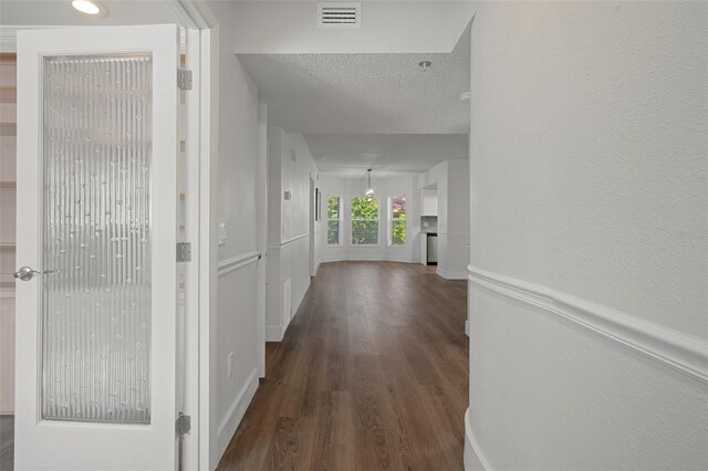 hallway featuring dark wood-type flooring and a textured ceiling