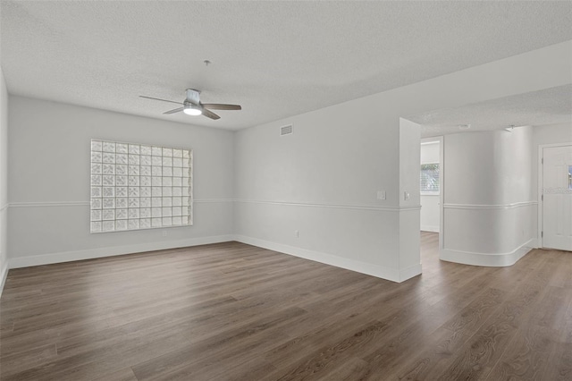 empty room with a textured ceiling, ceiling fan, and dark hardwood / wood-style floors