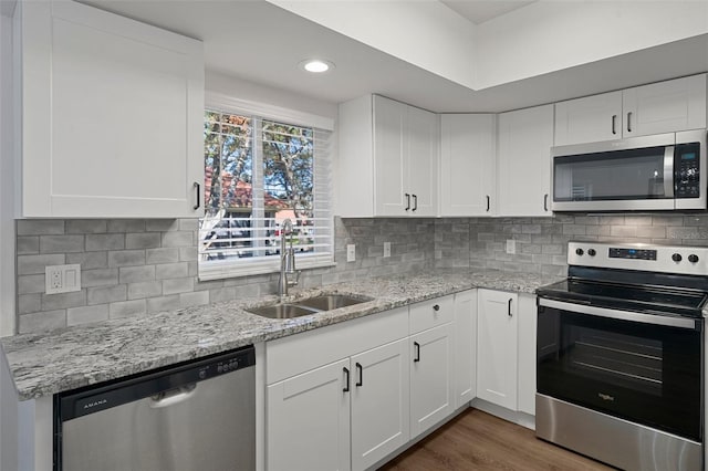 kitchen with white cabinetry, light stone countertops, sink, dark wood-type flooring, and appliances with stainless steel finishes