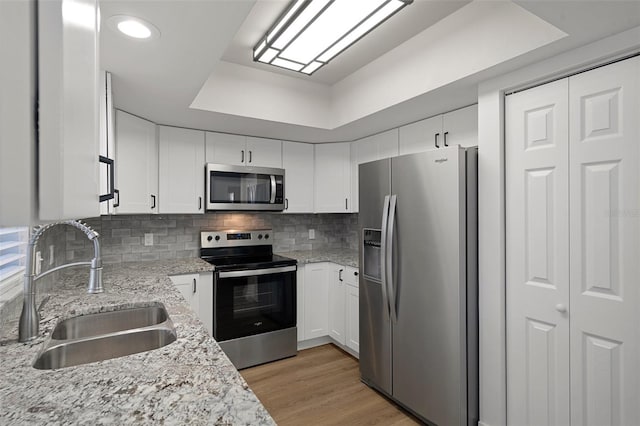 kitchen featuring white cabinetry, appliances with stainless steel finishes, sink, and light stone counters