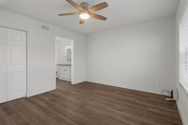 unfurnished bedroom featuring ceiling fan, a closet, dark hardwood / wood-style flooring, and ensuite bath