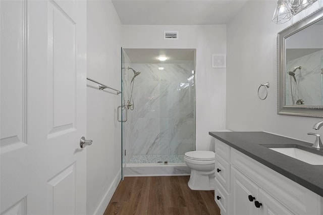 bathroom featuring toilet, hardwood / wood-style flooring, a shower with shower door, and vanity