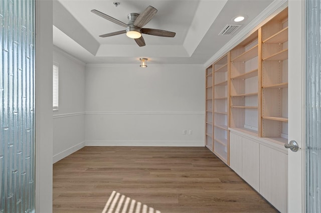 unfurnished room with light hardwood / wood-style floors, a tray ceiling, and ceiling fan