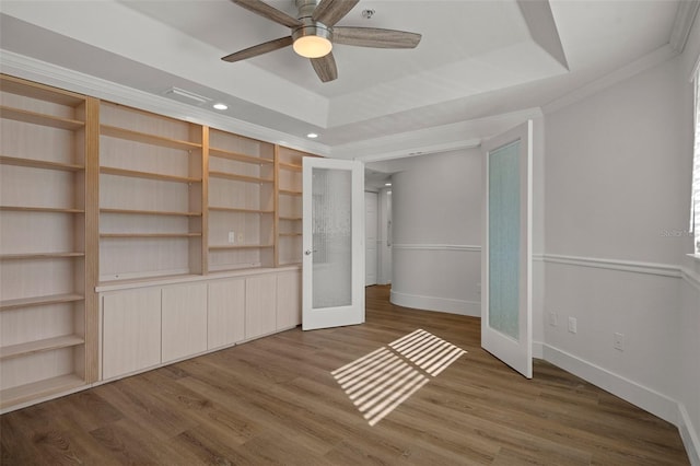 unfurnished bedroom with french doors, ceiling fan, a tray ceiling, ornamental molding, and dark hardwood / wood-style floors