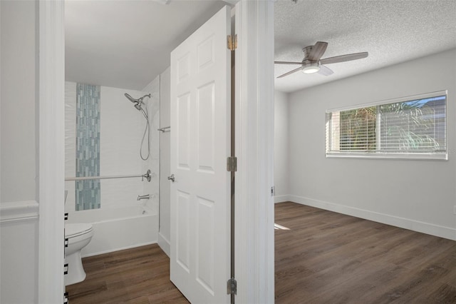 bathroom with hardwood / wood-style floors, shower / bathtub combination, a textured ceiling, ceiling fan, and toilet