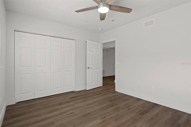 unfurnished bedroom featuring ceiling fan, a closet, dark hardwood / wood-style flooring, and a textured ceiling