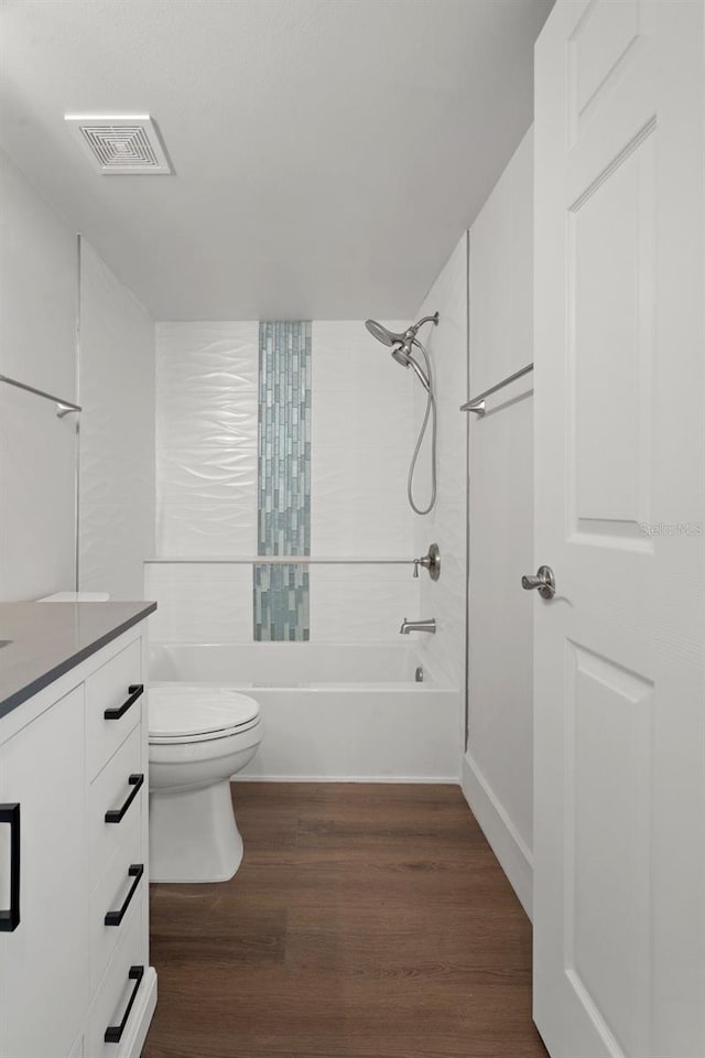 full bathroom featuring tiled shower / bath combo, wood-type flooring, vanity, and toilet