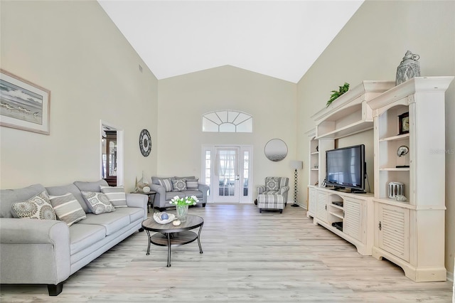 living room with french doors, light hardwood / wood-style floors, and high vaulted ceiling