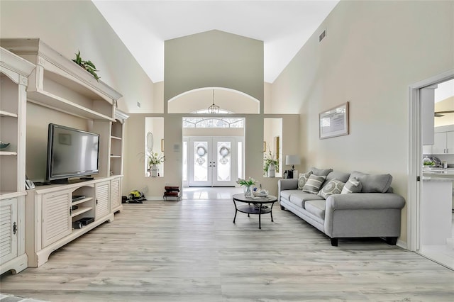 living room featuring light hardwood / wood-style flooring, high vaulted ceiling, and french doors