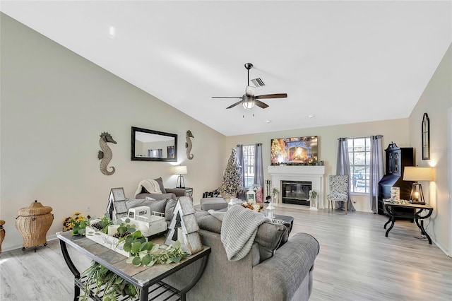 living room with ceiling fan, light hardwood / wood-style flooring, and vaulted ceiling