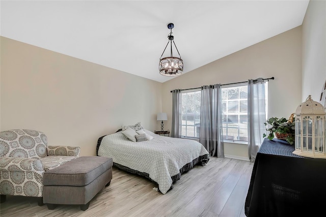 bedroom with a chandelier, light wood-type flooring, and vaulted ceiling