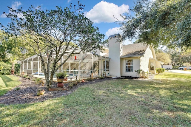 rear view of property with glass enclosure and a yard