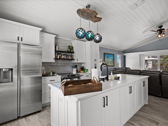 kitchen with stainless steel fridge, light wood-type flooring, white cabinetry, and an island with sink