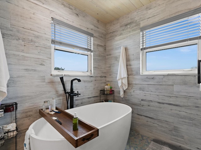 bathroom featuring wooden ceiling, plenty of natural light, and a tub